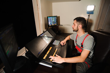 A lighting engineer works with lights technicians control on the concert show. Professional light mixer, mixing console. Equipment for concerts.