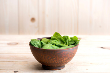 fresh green spinach leaves in ceramic bowl on wooden tabletop