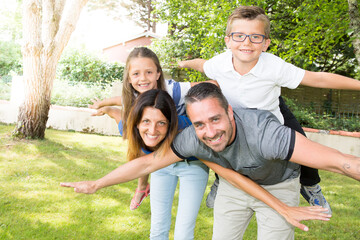 mother and father parents giving piggyback ride to kids in countryside