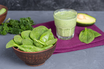 bowl of fresh spinach leaves and antioxidant drink  with avocado on linen