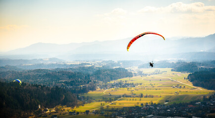 Two paragliders are flying in the valley.