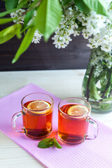 Two cups of black tea with lemon,  cherry flowers. Still life. Food industry, tea packing, restaurant business