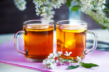 Two cups of black tea with lemon,  cherry flowers. Still life. Food industry, tea packing,...