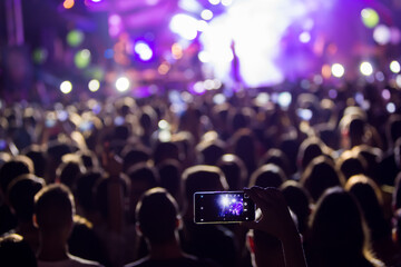 Hand with a smartphone records live music festival