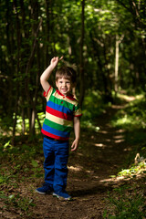 young boy playing in the green forest