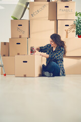 Young Caucasian girl using duct tape for packing carton boxes