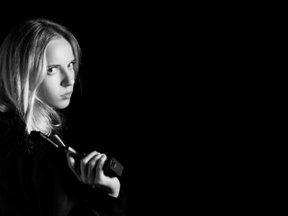 serious girl with gun on black background with copy space, monochrome