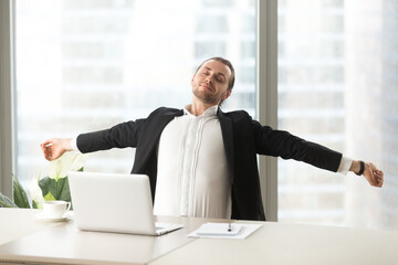 Businessman stretching out at desk with laptop. Office worker doing relaxing exercises at workplace to relieve physical fatigue Manager make deep breath of fresh air, relaxed after finishing work