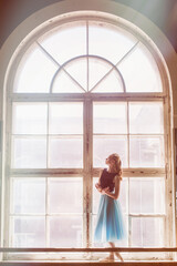 Ballerina is posing in front of a large window
