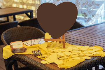 Large brown heart on the table next to the little yellow hearts for the wishes of the guests.  Writing wishing and congratulation to bride and groom