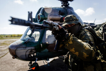 Photos of a group of military men with a gun in front of a helicopter