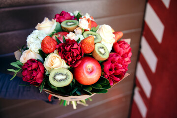 The original edible bouquet of marshmallow, apples, strawberries and flowers in woman's hand.