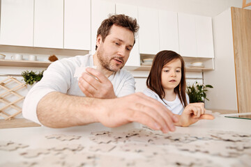 Inspired father and daughter doing a jigsaw puzzle together