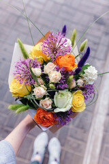 Stylish bouquet in orange and purple colors. Bouquet of rose and ranunculus flowers in woman's hand
