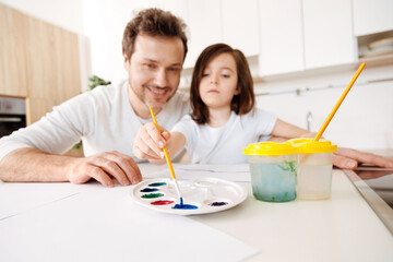 Little girl taking blue colour from palette