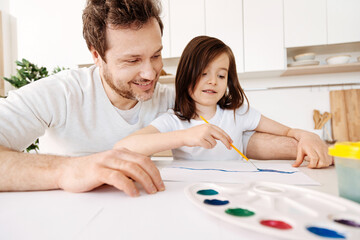 Happy father watching his daughter painting