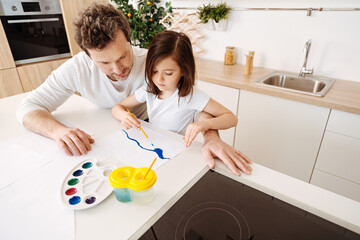 Young father being curious about his daughters picture