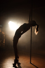 Obraz na płótnie Canvas Young sexy woman exercise pole dance on a dark background