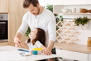 Father and daughter looking at each other while painting