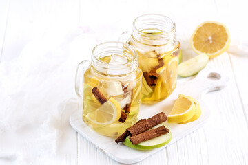 Infused water Fresh homemade ice tea with apple citrus and cinnamon Two glass jars with cold tea