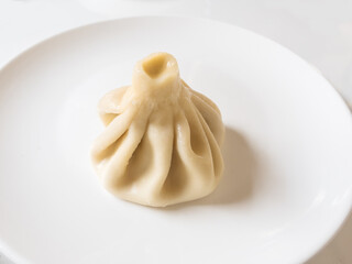 Dumplings Khinkali, manti, pozi, buuzi, poses, xiaolongbao with meat on white plate. Balkan, Caucasian, Asian cuisine.