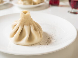 Dumplings Khinkali, manti, pozi, buuzi, poses, xiaolongbao with meat on white plate. Balkan, Caucasian, Asian cuisine.