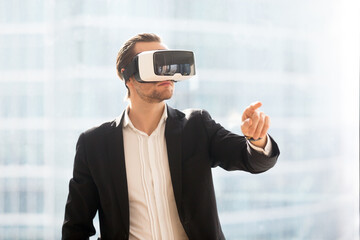 Businessman in VR headset working in office augmented reality. Man using virtual reality glasses to interact with objects in cyberspace software. Future technology and innovations concept for business