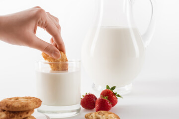 Close-up partial view of person eating cookies with fresh milk and strawberries