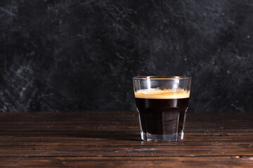 glass of freshly made dark coffee on wooden tabletop
