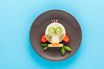 Funny colorful breakfast for child in shape of owl isolated on blue