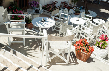 White Greek stairs with tables and chairs. Typical Greek street with flowers