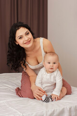 Happy smiling mother and baby lying on bed