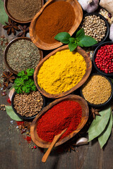 assortment of various spices and herbs on a wooden table, vertical top view