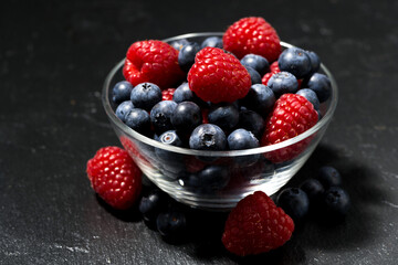 fresh berries in a glass bowl on black background