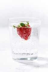 glass of carbonated water with fresh strawberries, vertical