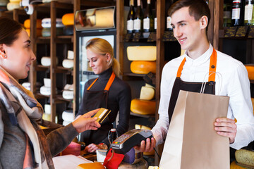 Customer paying for order of cheese in grocery shop.