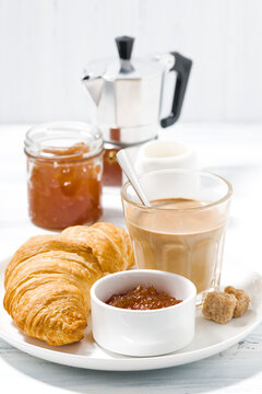 coffee with milk and croissants with jam on white table, vertical