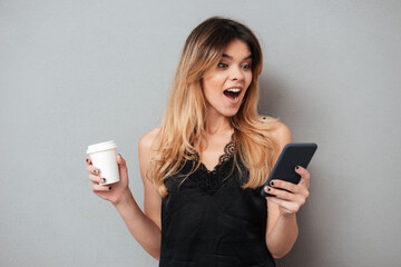 Portrait of a young excited woman looking at mobile phone