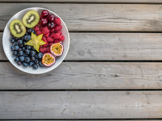 Overhead view of Blueberry, raspberry, kiwi, starfruit, passion fruit on plate.