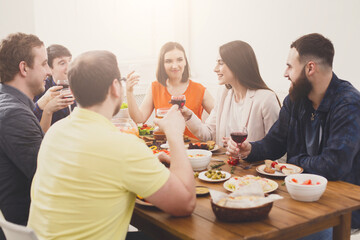 Group of happy young people at dinner table, friends party