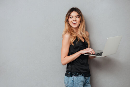 Portrait of a pretty girl standing and holding laptop computer