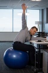 Executive performing stretching exercise on fitness ball