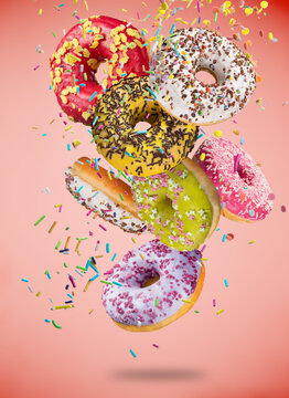 Tasty doughnuts in motion falling on pastel blue background.