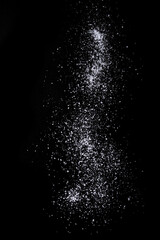 Sifting sea salt over black background. Isolated