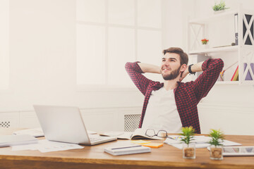 Young relaxed businessman with laptop in modern white office