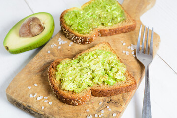 Healthy avocado toast with spices on whole wheat bread with fork and avocado