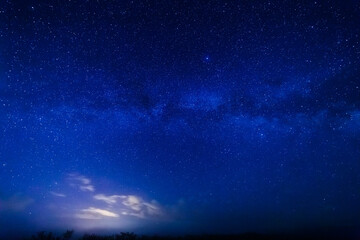 Naklejka na ściany i meble Milky way and starry sky. Bright cloud in the background.
