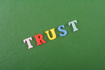 TRUST word on green background composed from colorful abc alphabet block wooden letters, copy space for ad text. Learning english concept.