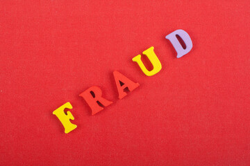 FRAUD word on red background composed from colorful abc alphabet block wooden letters, copy space for ad text. Learning english concept.