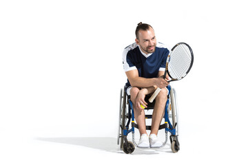 Fototapeta na wymiar Smiling young man with tennis racquet sitting in wheelchair and looking away